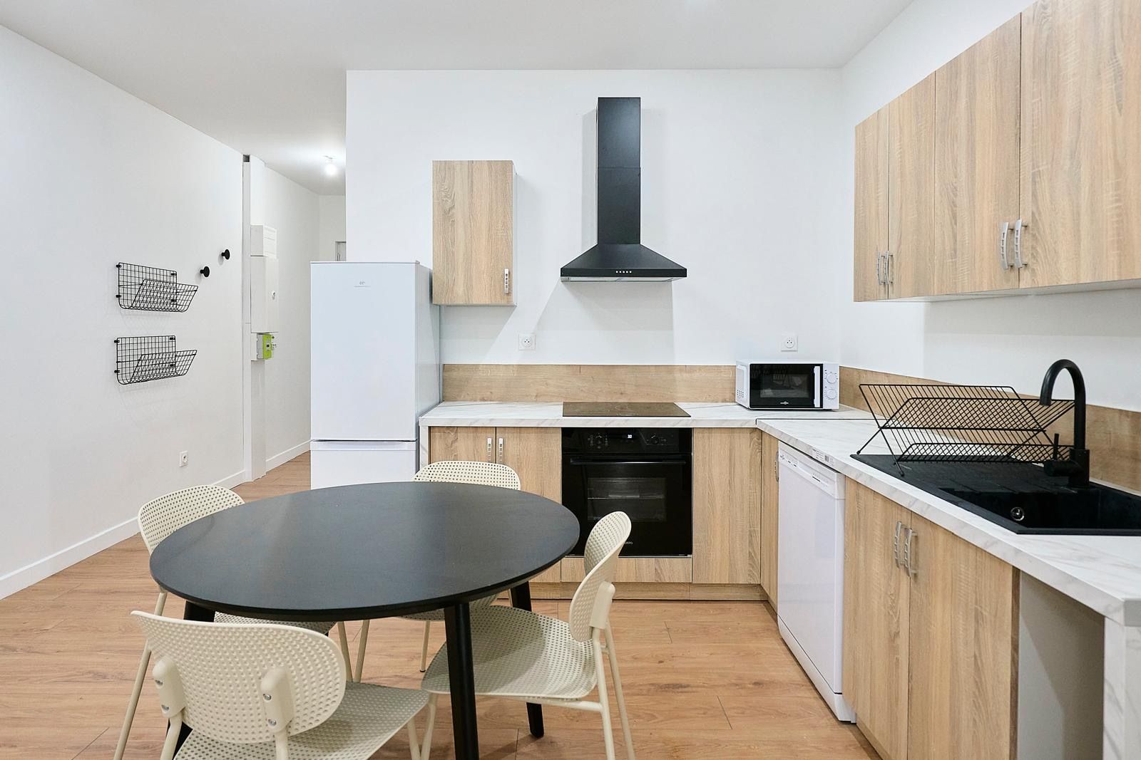 Cuisine équipée en bois clair avec table ronde noire