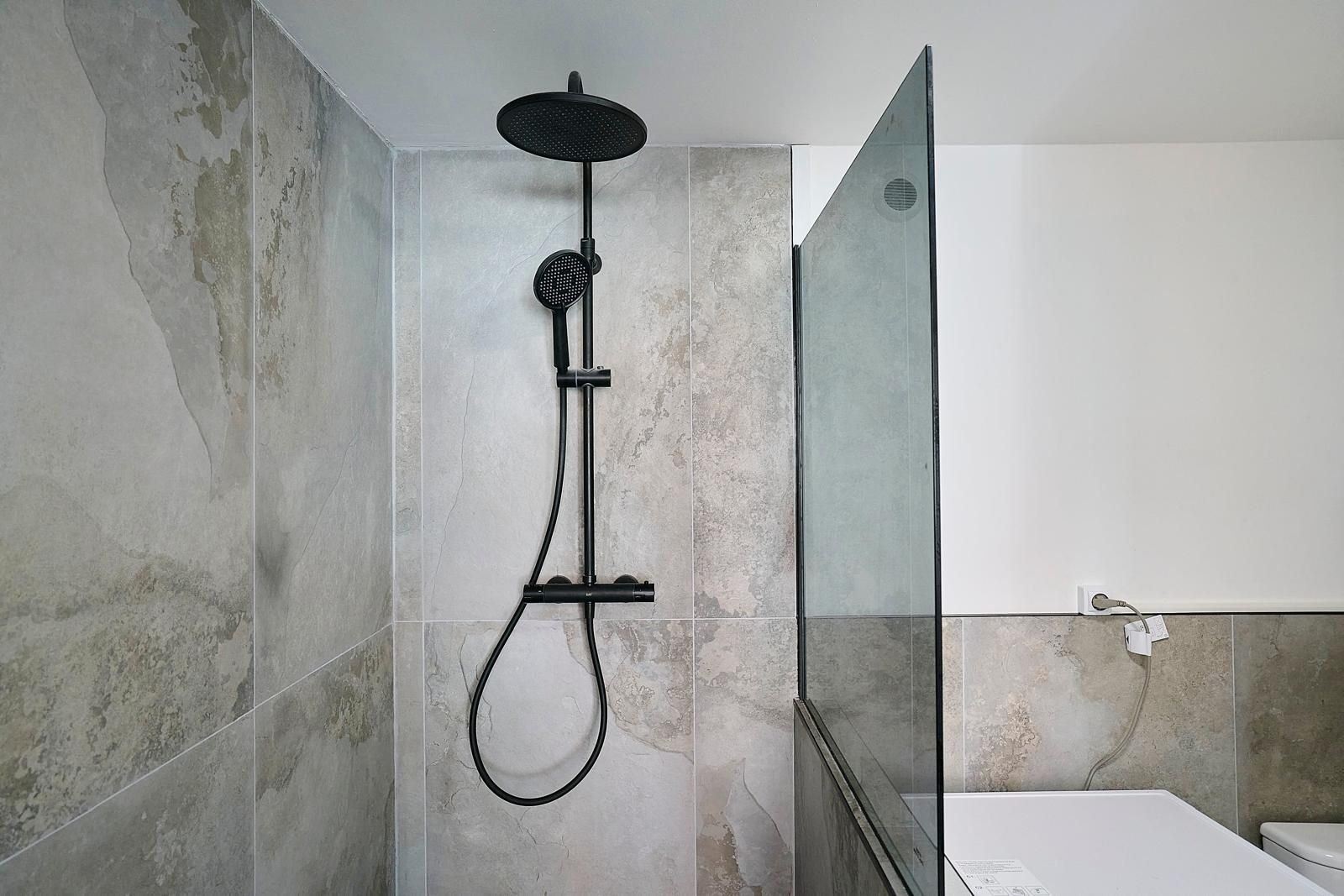 Douche à l'italienne, carrelage effet pierre, robinetterie noire